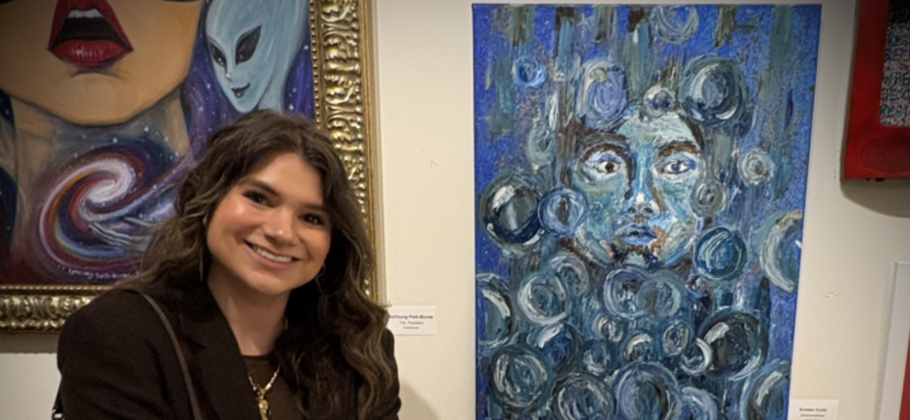 Kristin Corbi poses beside her award-winning painting titled “Overwhelmed.”