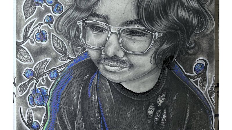 A portrait of a young man wearing a sweater and translucent glasses, surrounded by branches of blueberries.