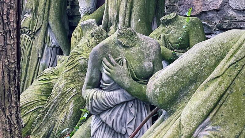 a headless statue of a female body among the ruins of other headless statues