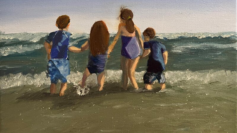 Four children on beach holding hands as the shallow ocean waves splash at their feet.