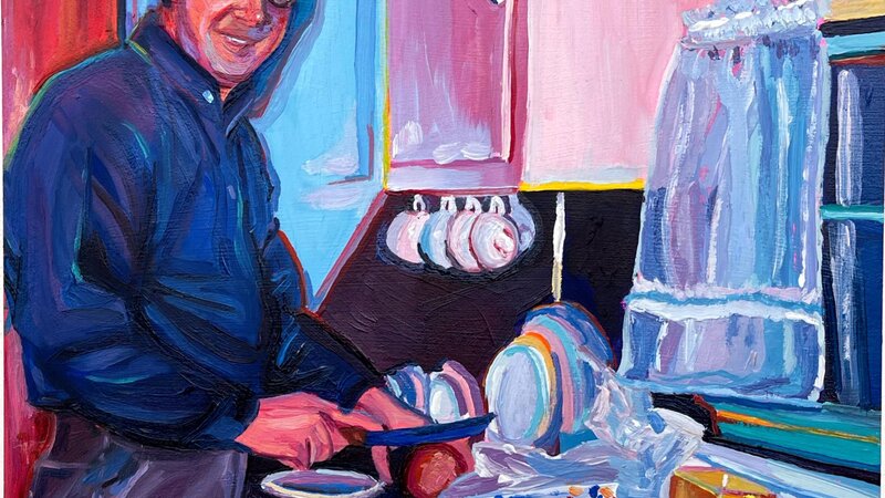 A mid century man preparing a sandwich with wonder bread in his pink and blue kitchen. He's smiling at the camera. 