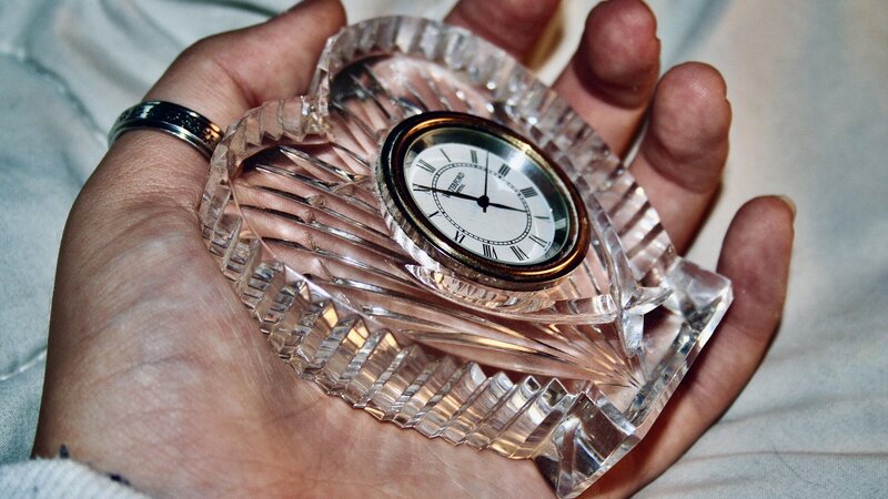 A cold colored hand losing grip with a heart shaped glass clock rested the palm of a hand. 