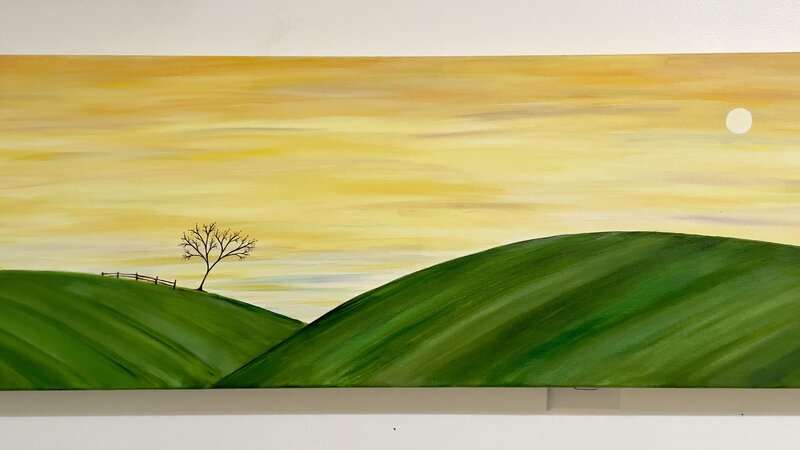 golden sky with moon. Rolling green hills with one tree