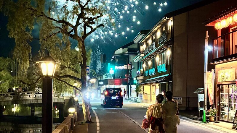 Nighttime photo of two women watching fireworks in a small Japanese town.