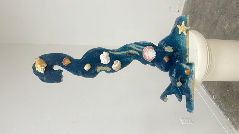 Abstracted sculpture of a wave with sand and seashells 