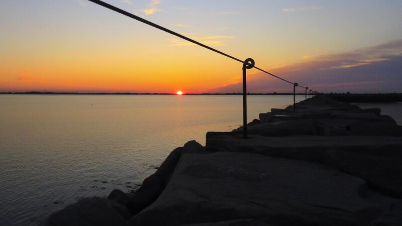 Sunrises over the Jetty in Plymouth, Massachusetts leaving just a silhouette of the Jetty and railing 