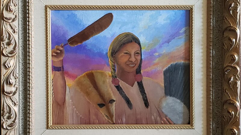 The Healer raises her sacred feather to bless the sunrise dancers