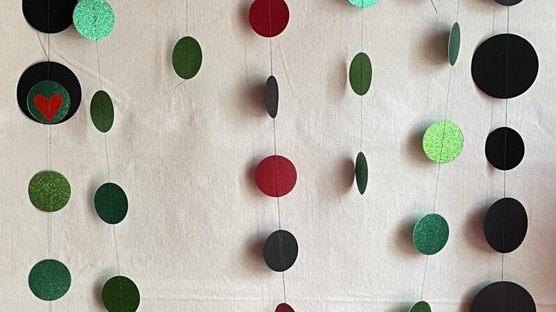 Installation created out of red, black, and green paper, plastic, wire and wood.