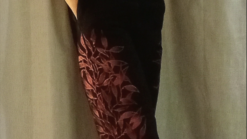 Black, short sleeved denim jumpsuit, with metallic red vines painyted up the sides of the legs