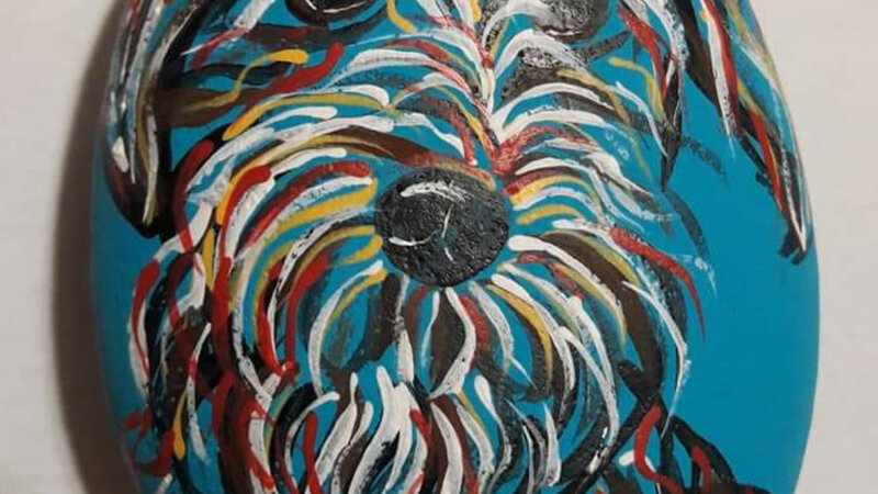 Abstract dog painted with acrylics on rock in multiple colors.