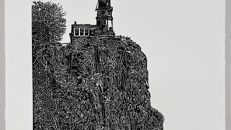 A carved image of Split Rock Lighthouse located on Lake Superior. It is a black and white, carved relief print that is incredibly dense and detailed depicting the light house, rocky ledge, and shoreline.