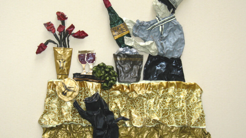 sculpture on paper of a chef and his unruly cat, made entirely from wine capsules