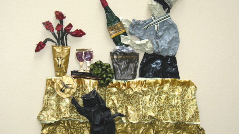 sculpture on paper of a chef and his unruly cat, made entirely from wine capsules