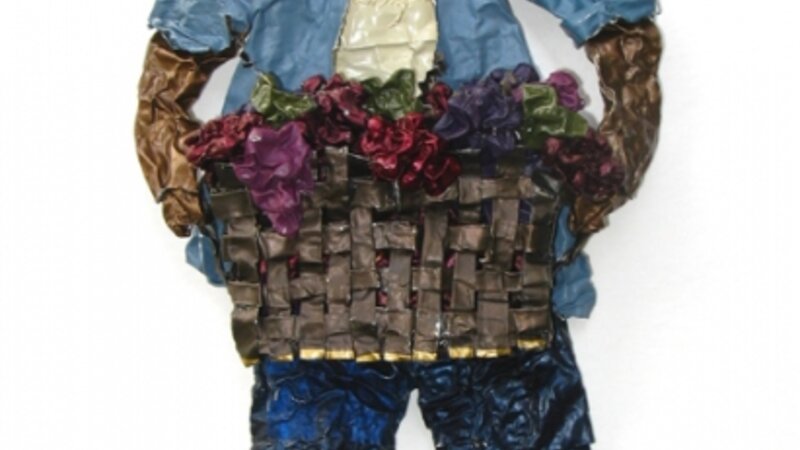 A sculpture on paper made from wine capsules of a field worker carrying a basket of grapes 