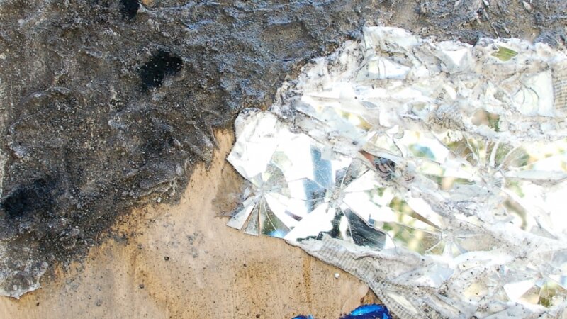 blue figure on burnt wood with broken glass and ashes