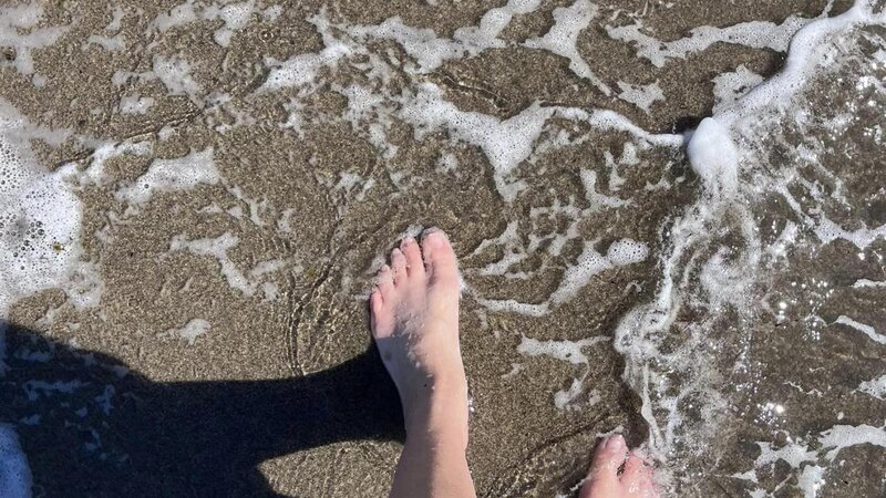 feet in the ocean casting a shadow