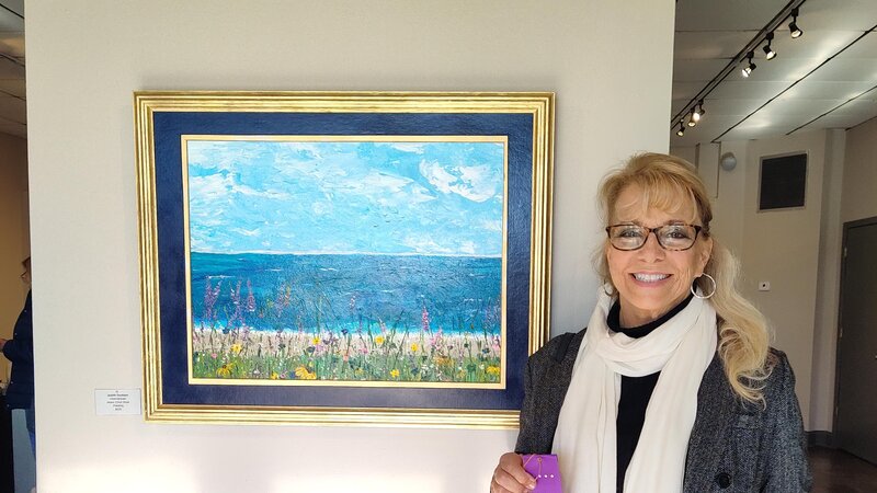 ocean scene with blue sky filled with clouds and flowers in the foreground