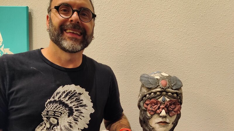 sculpture of bust of a head with flowers over the eyes and elaborate head covering