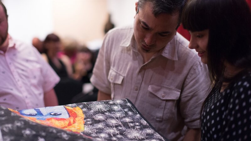 11th Annual Exhibit Attendees taking a closer look at the details of Jodi Davila's award winning textile piece.