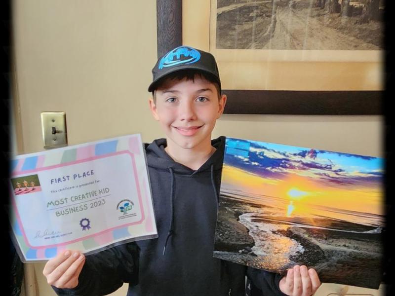 Asher Ryan holding a copy of Sunrise at Nelson which sold at MassArt Auction and a certificate for first prize in a local children's Business Fair 