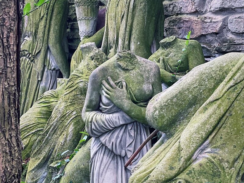 a headless statue of a female body among the ruins of other headless statues