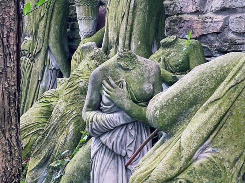 a headless statue of a female body among the ruins of other headless statues