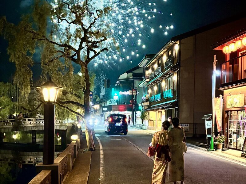 Nighttime photo of two women watching fireworks in a small Japanese town.