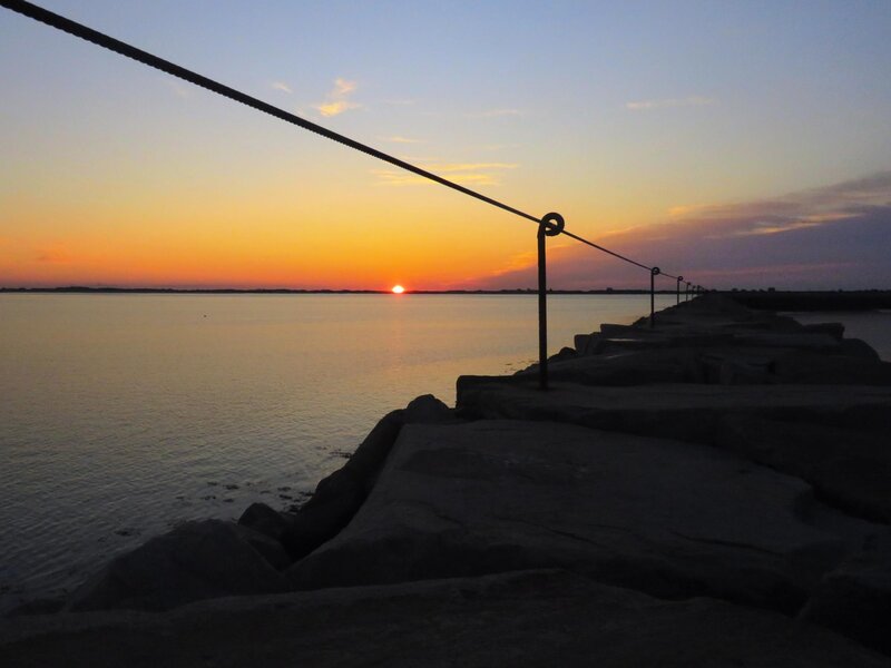 Sunrises over the Jetty in Plymouth, Massachusetts leaving just a silhouette of the Jetty and railing 