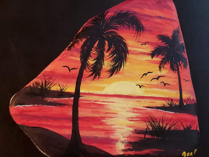 Image of red and gold sunset with sun, two palm trees and seagulls, painted on Santorini stone.