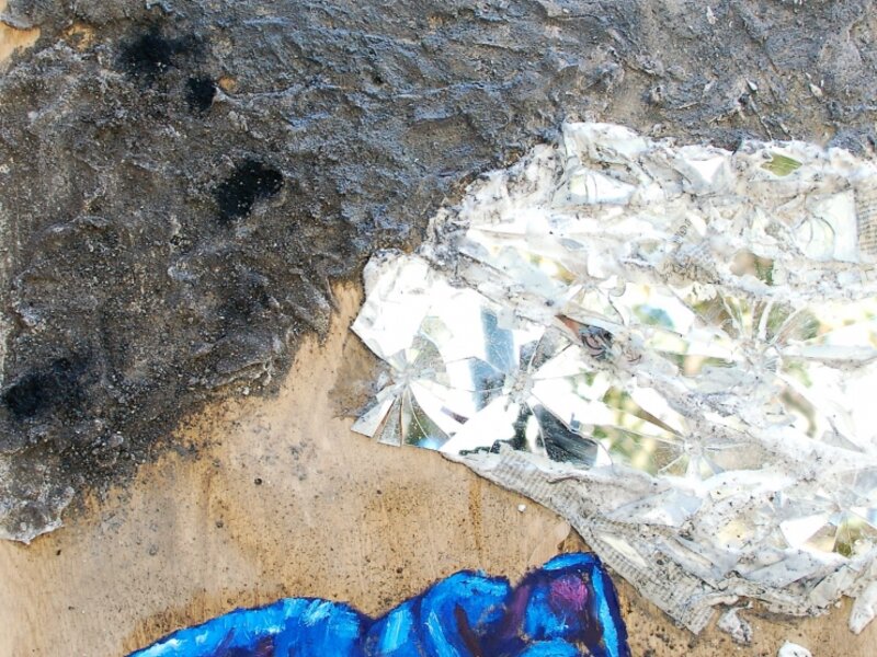 blue figure on burnt wood with broken glass and ashes
