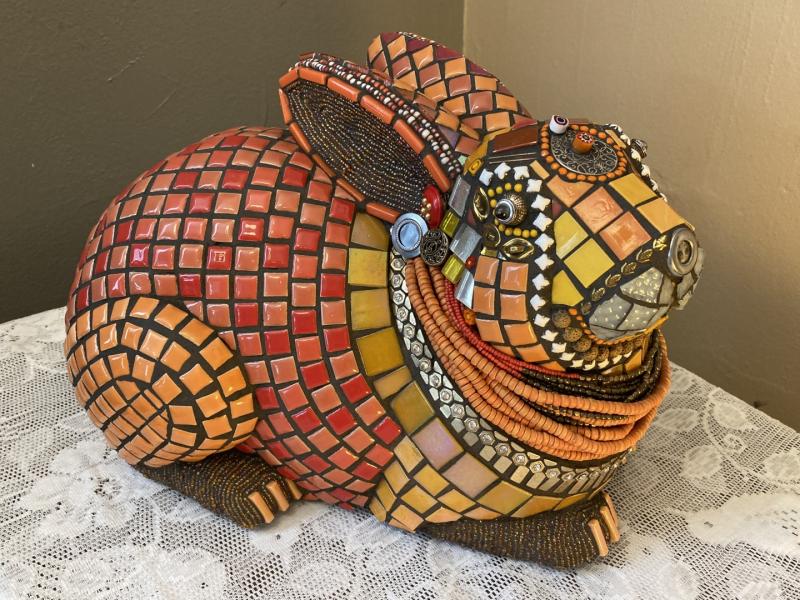 rabbit sculpture covered in red, orange, white, and metal tesserae