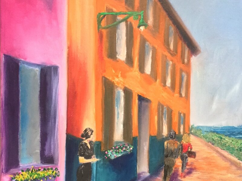 A woman watching people pass as she leans between two colorful buildings.