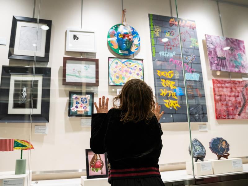 a child looking up at the display case filled with artwork