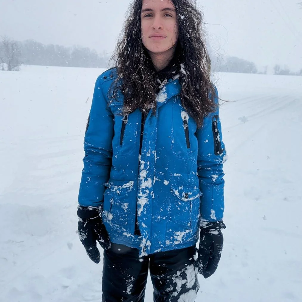 A long-haired teen standing in the snow