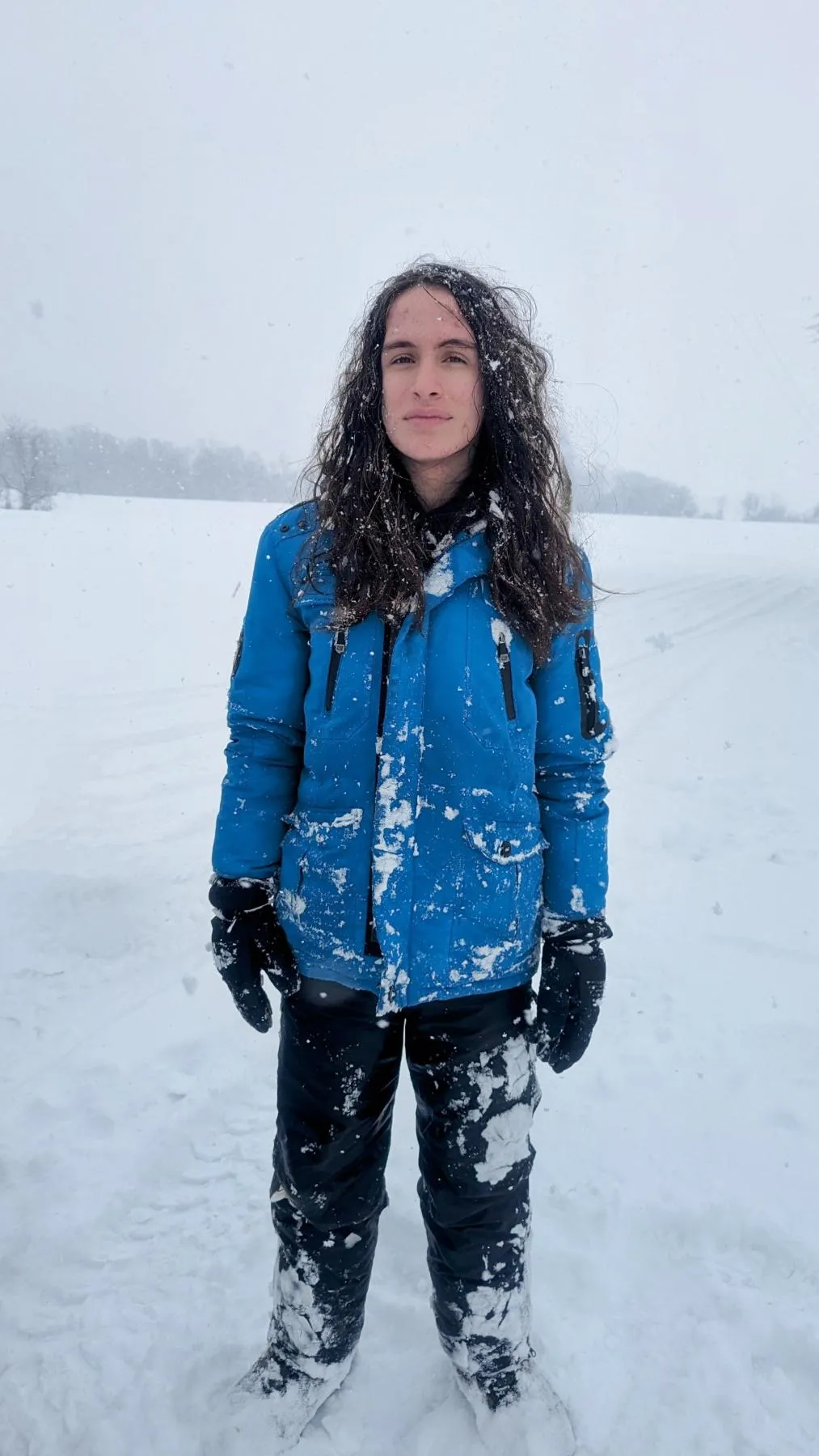 A long-haired teen standing in the snow