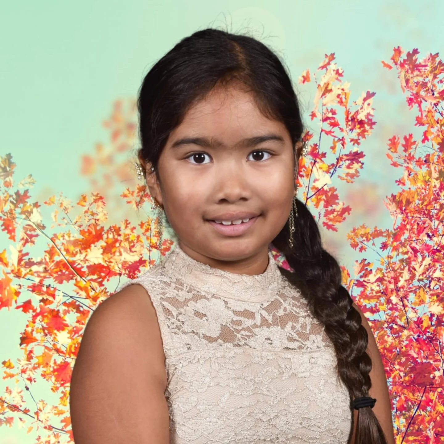 A young brown girl with a black side braid wearing a gold dress.