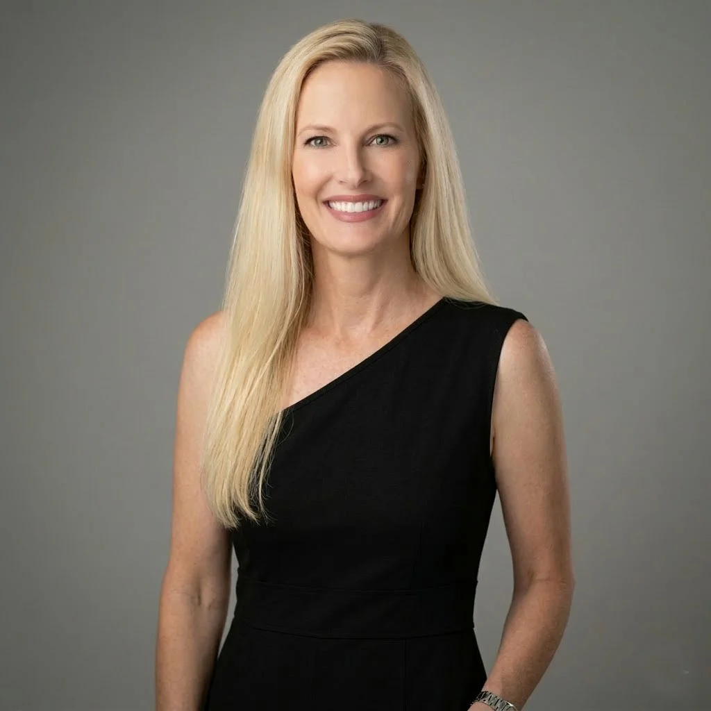 Picture of smiling female artist with long blonde hair. She is wearing an asymmetrical black sleeveless dress.