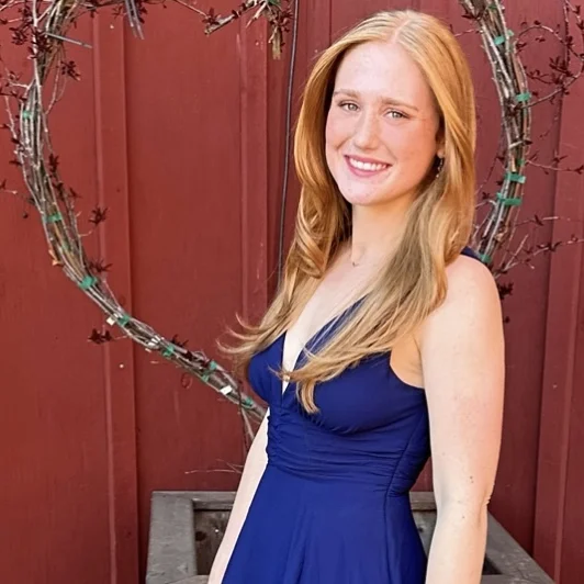 Woman in a blue dress, smiling at the camera.
