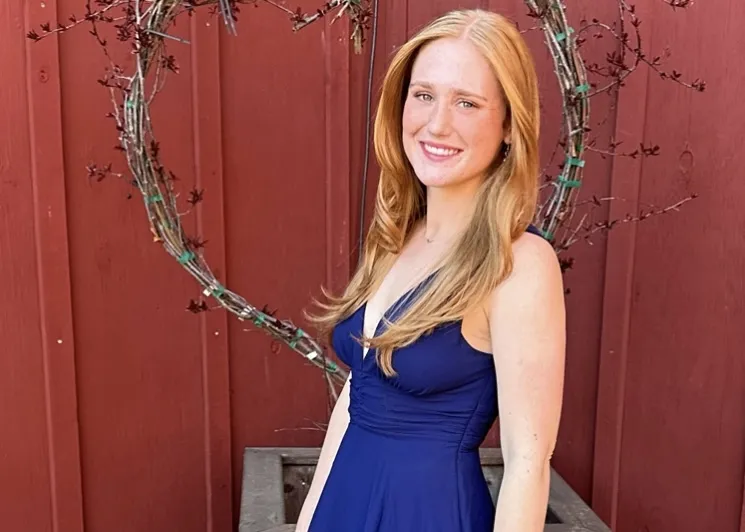 Woman in a blue dress, smiling at the camera.