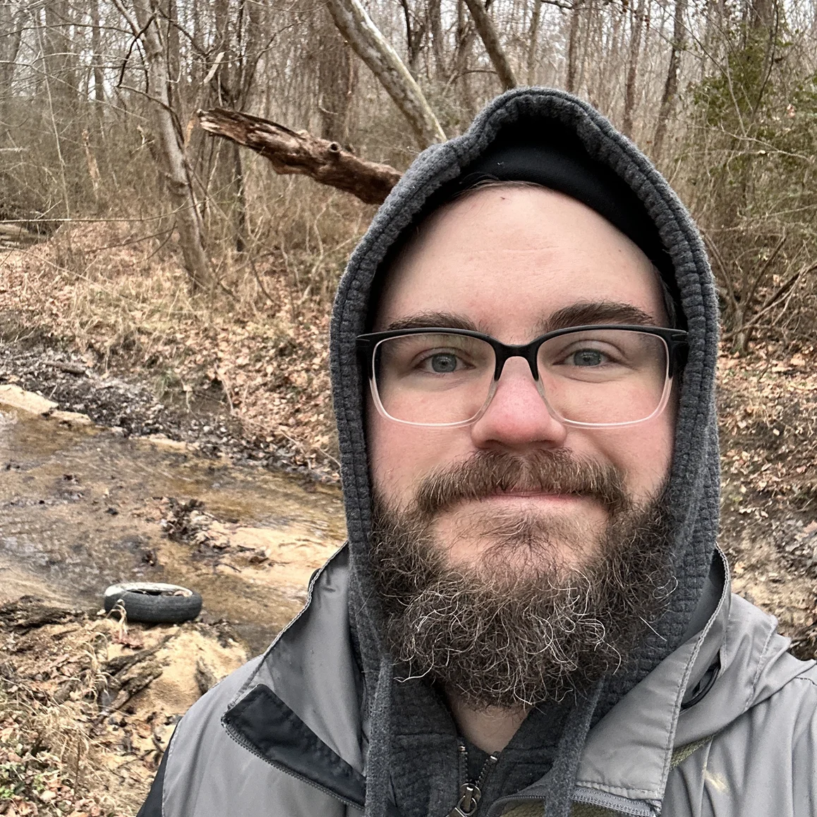 Profile Photo: Stewart Pillow standing next to a creek surrounded by the forest. 