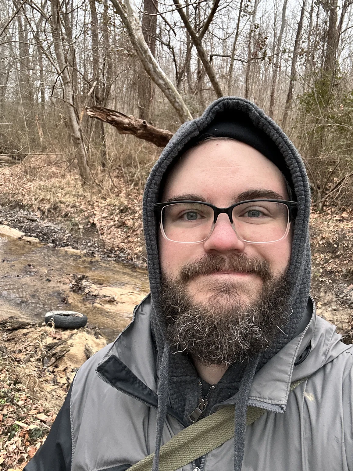 Profile Photo: Stewart Pillow standing next to a creek surrounded by the forest. 