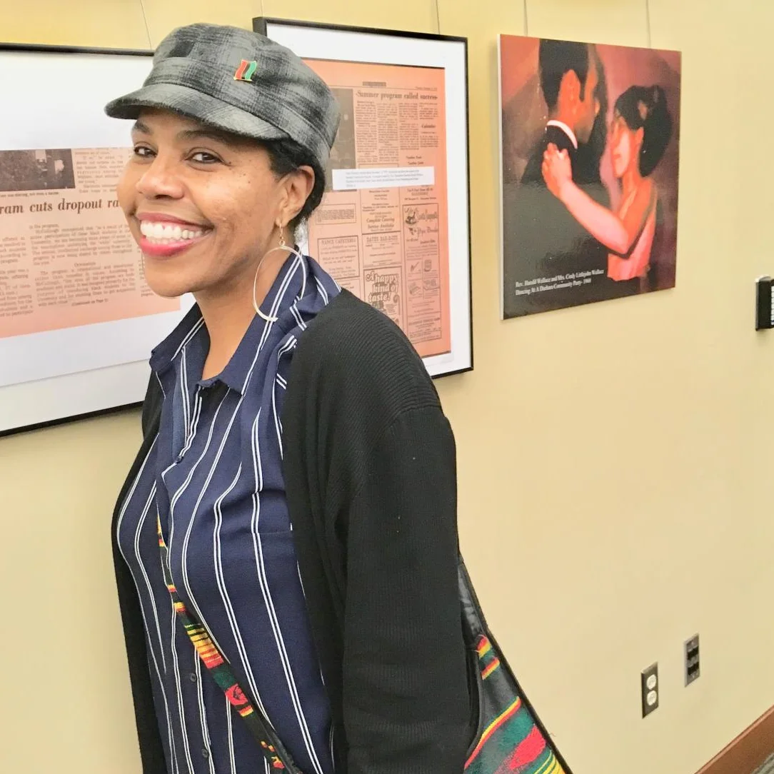 Toya at her first curated exhibit titled, "Documenting Daddy's Days At Duke Part1-Vice Chancellor Emeritus Harold Gene Wallace Sr. - A Living Legend". To the right, a photo of her parents dancing at a Duke University event, circa 1970. (Duke University Exhibit Wall, 2019))