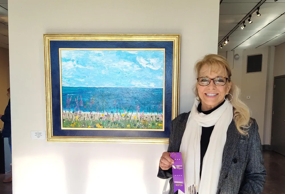 ocean scene with blue sky filled with clouds and flowers in the foreground