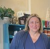 Portrait of artist, Laura Hill, standing in front of bookcase