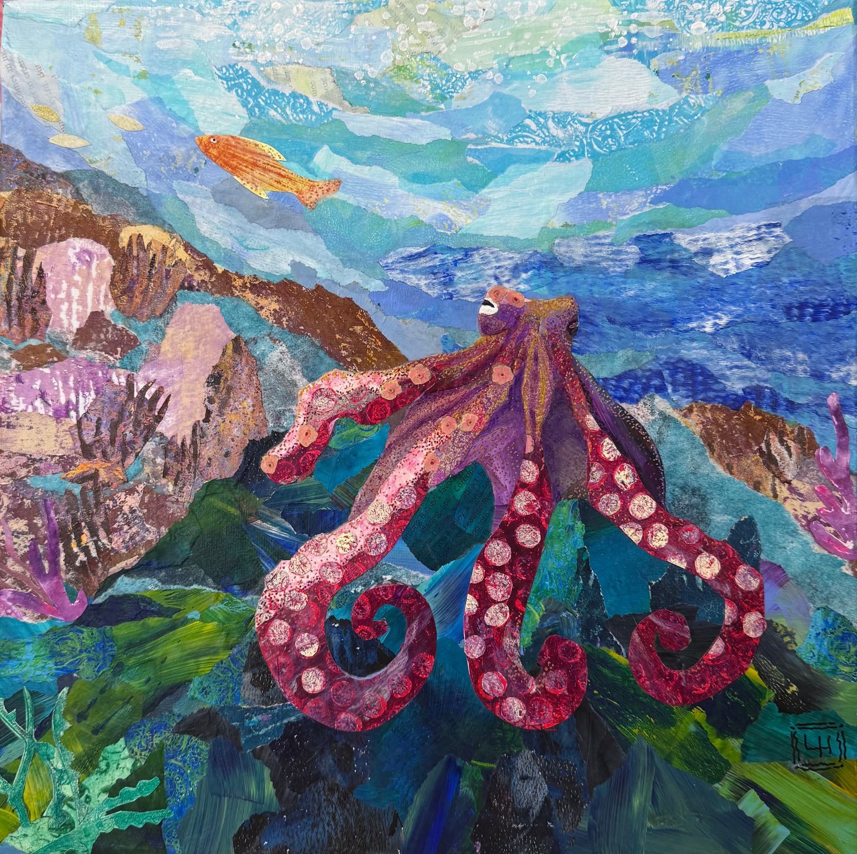 Mixed media torn-paper collage depicting a resting octopus on ocean rocks with coral and swimming fish in background.