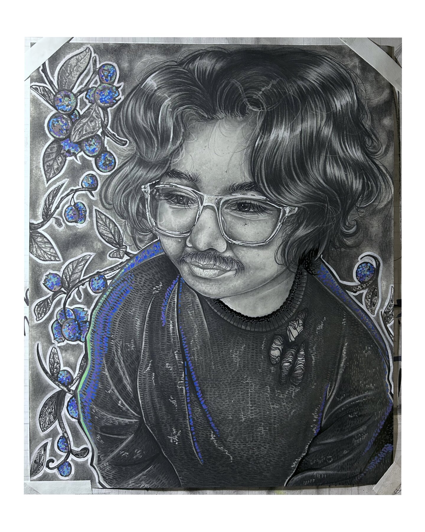 A portrait of a young man wearing a sweater and translucent glasses, surrounded by branches of blueberries.