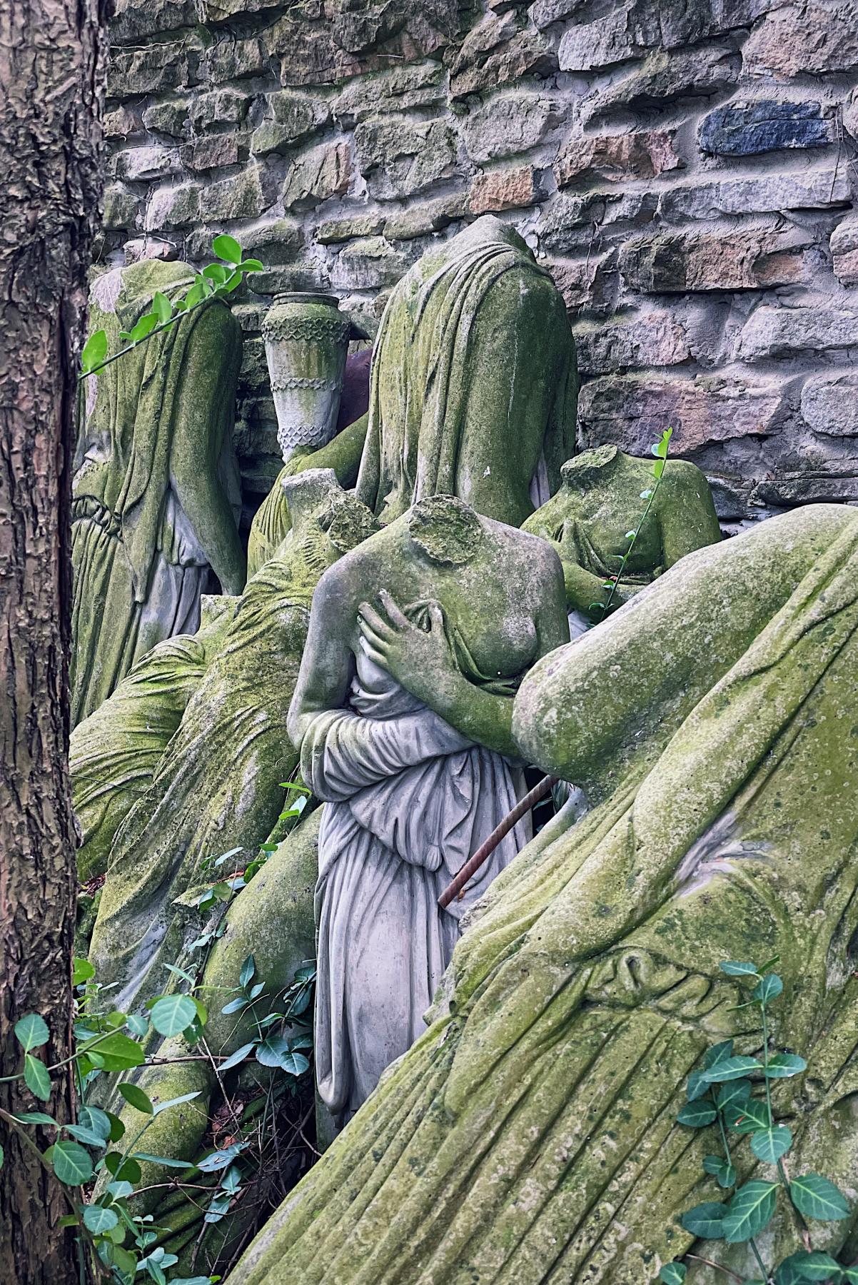 a headless statue of a female body among the ruins of other headless statues