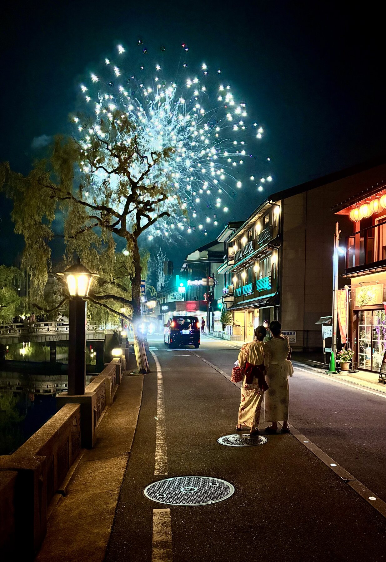 Nighttime photo of two women watching fireworks in a small Japanese town.