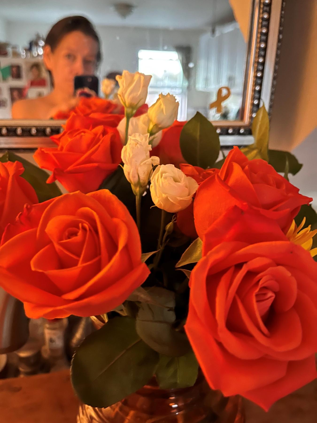 coral roses in a vase in front of a reflection