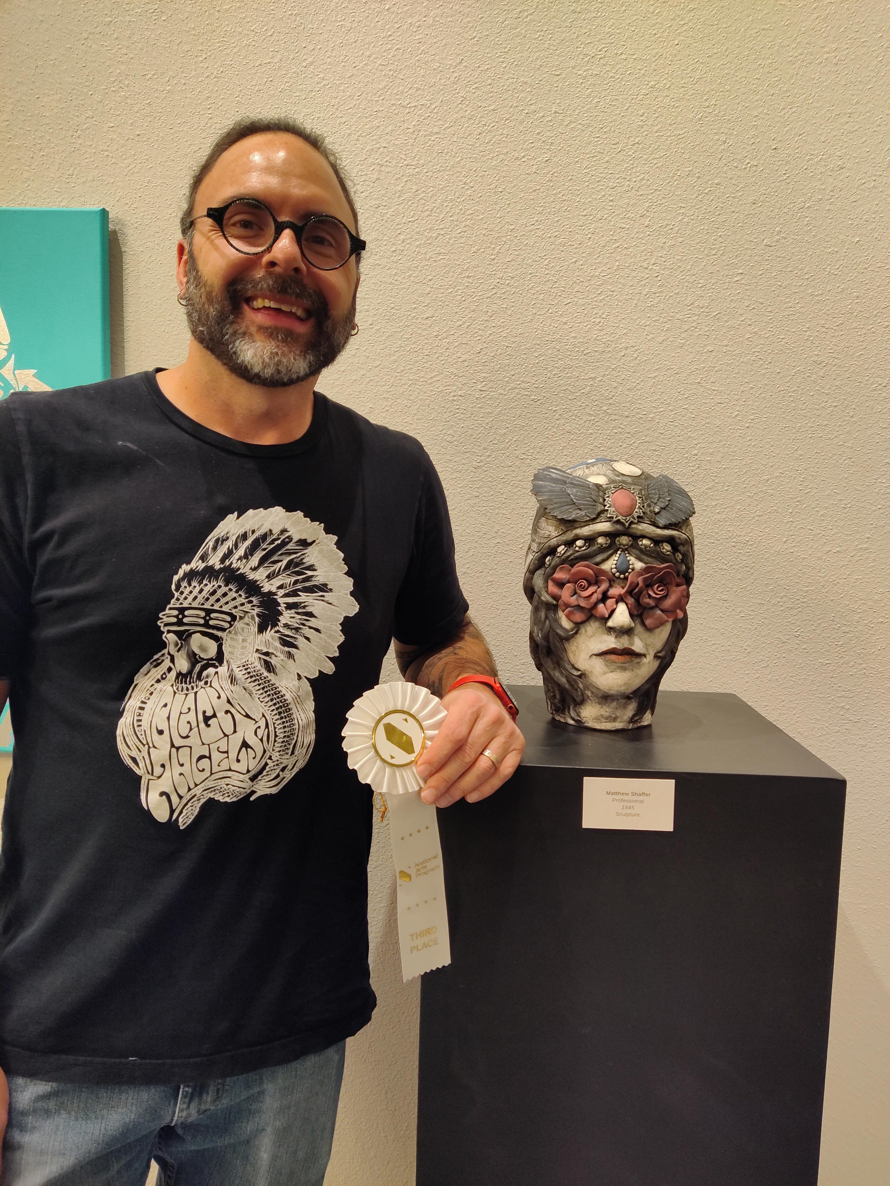 sculpture of bust of a head with flowers over the eyes and elaborate head covering